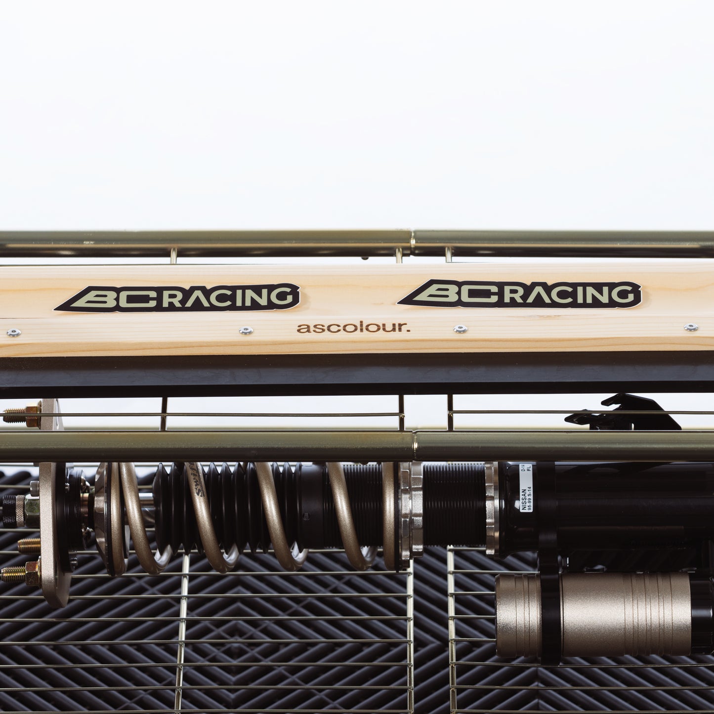 BC Racing gold and black sticker on shelf with coilover on bottom