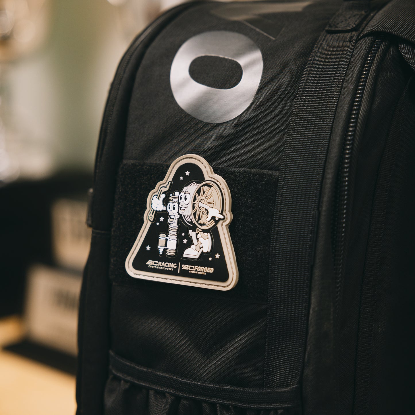 PVC patch of BC Racing wheel and coilover characters on a black backpack