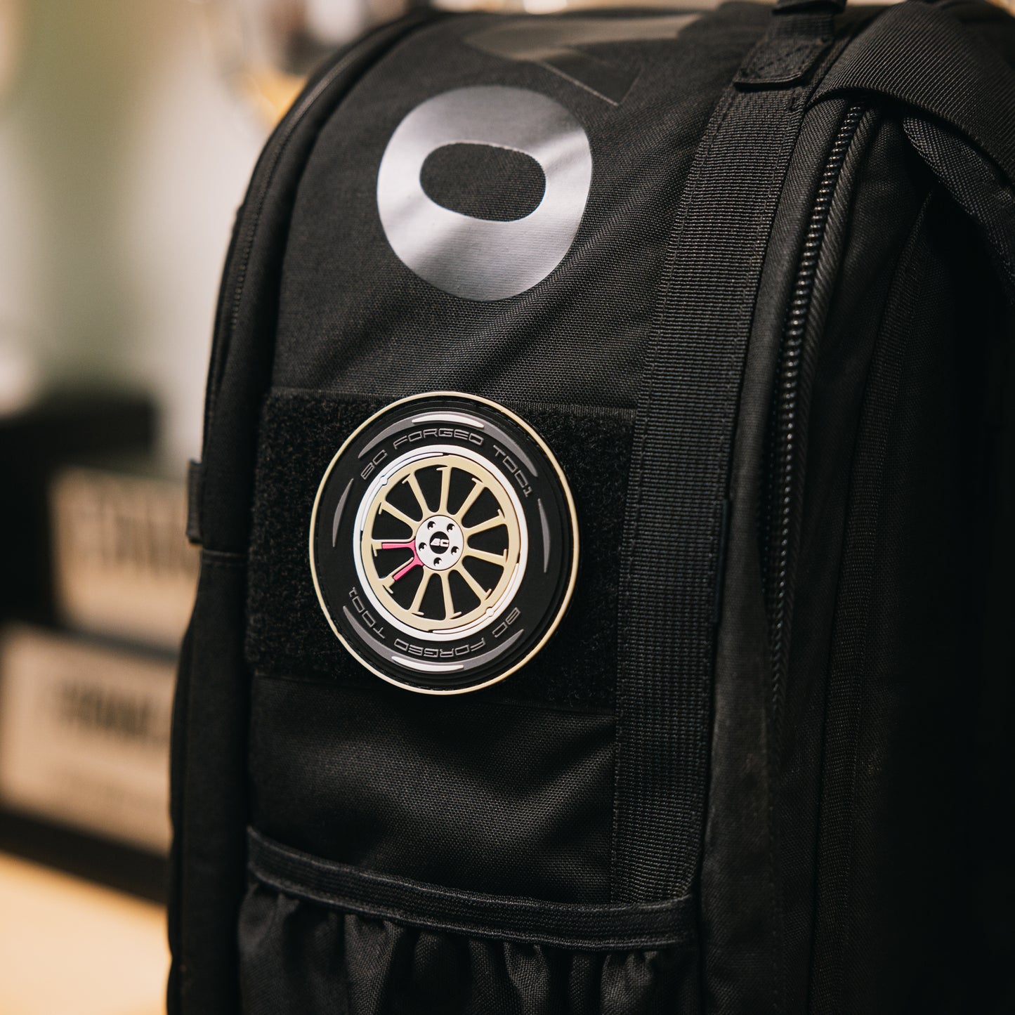 PVC patch of a BC Forged TD01 wheel in gold on a black backpack